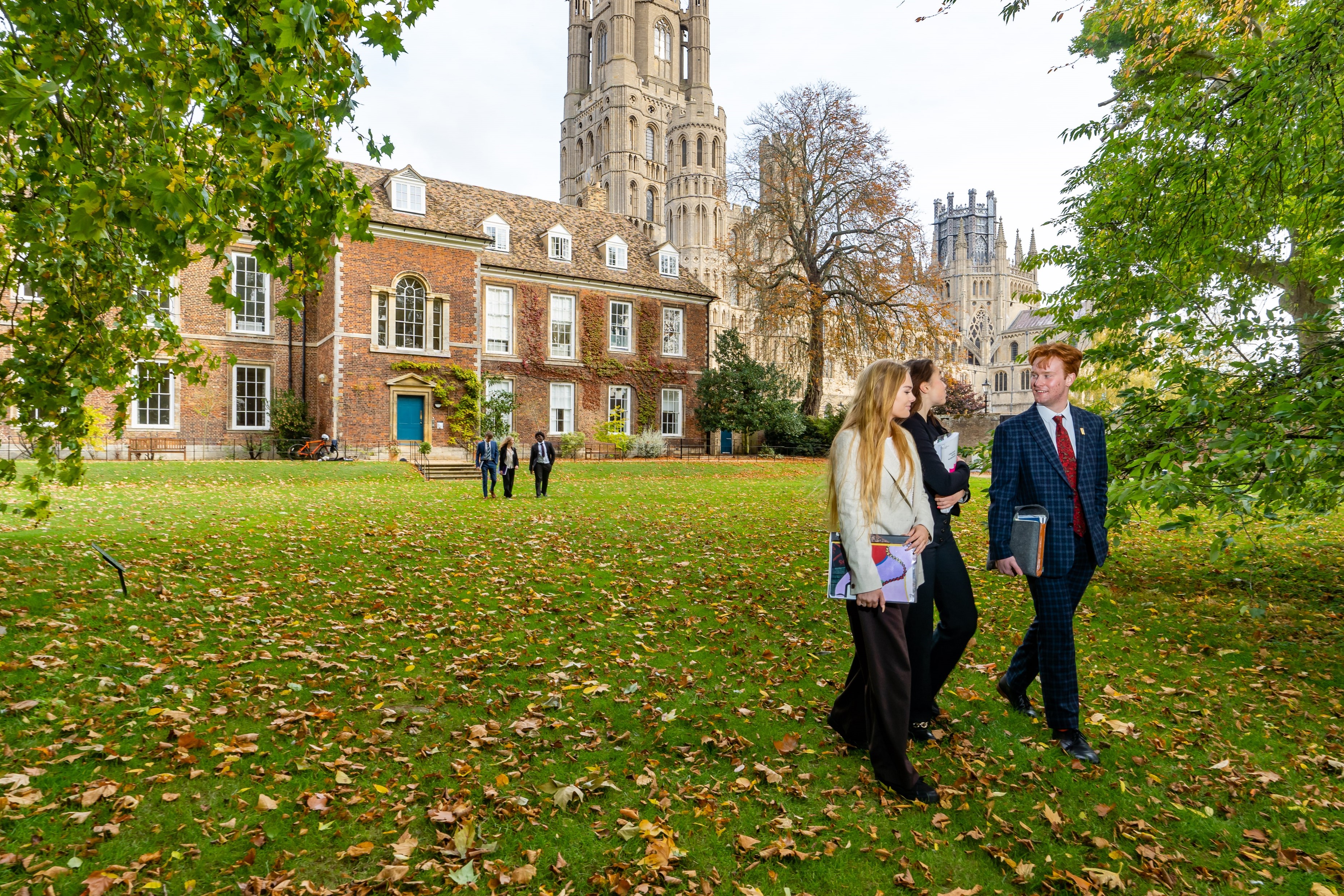 A group of Sixth Form students walking in the Old Palace gardens at King's Ely, a private Sixth Form boarding school near Cambridge.