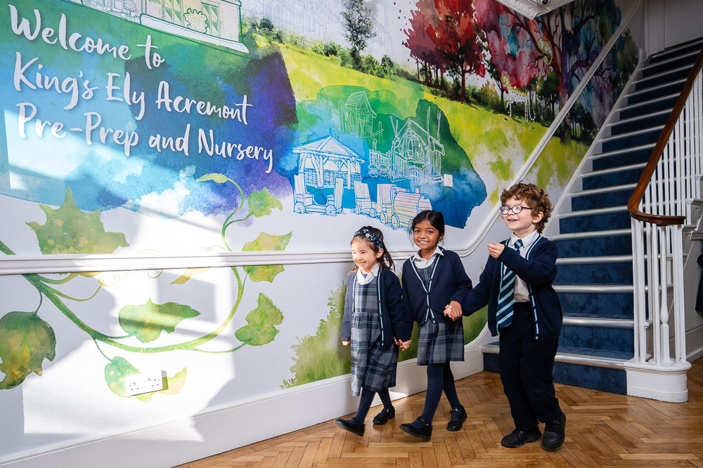 Three King’s Ely Pre-Prep students walking together in the Acremont entrance hall