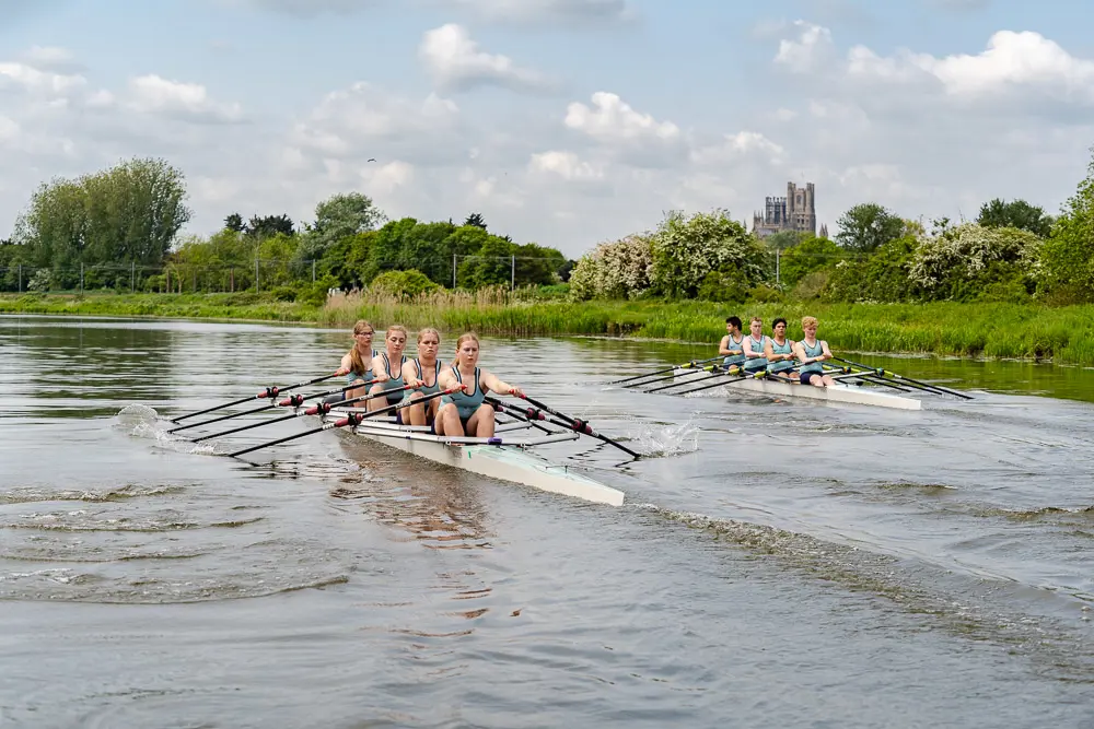 Kings Ely Senior Rowing team rowing on the River Ouse with King's Ely Cathedral in the background 